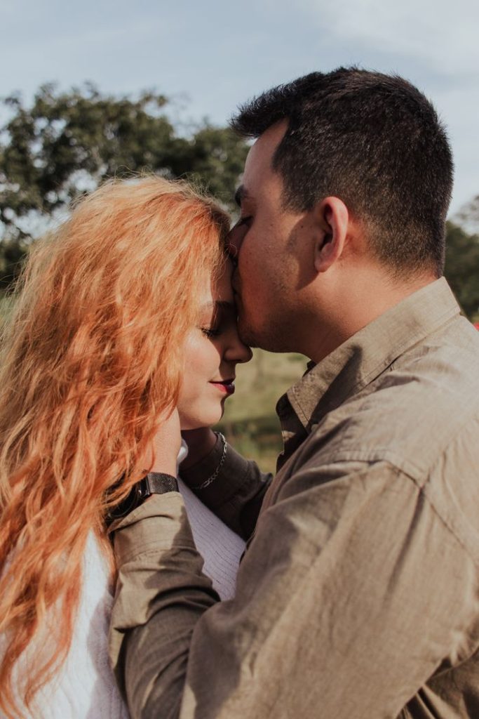 A couple shares a tender moment outdoors, symbolizing love and affection.