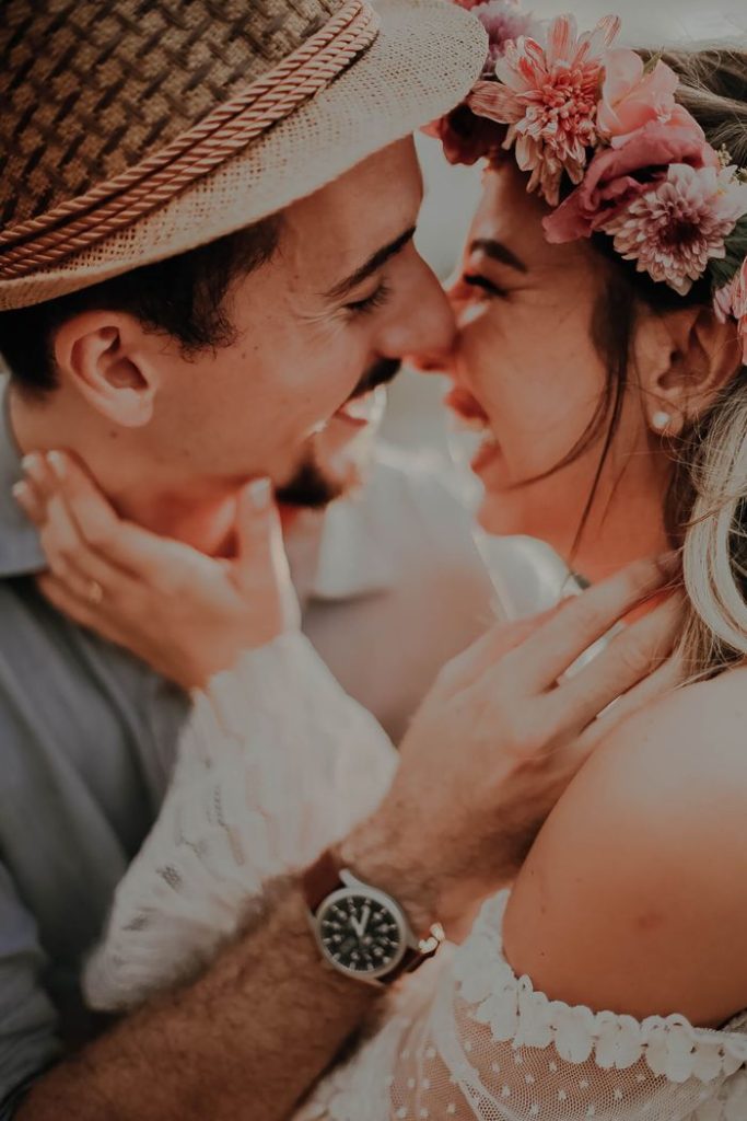 Joyful couple embracing, wearing floral accessories, exuding love and romance.