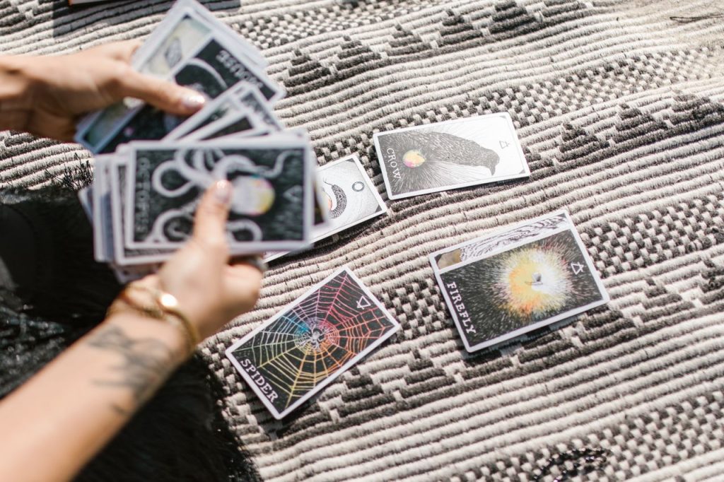 Hands dealing tarot cards for a reading on a stylish geometric rug.